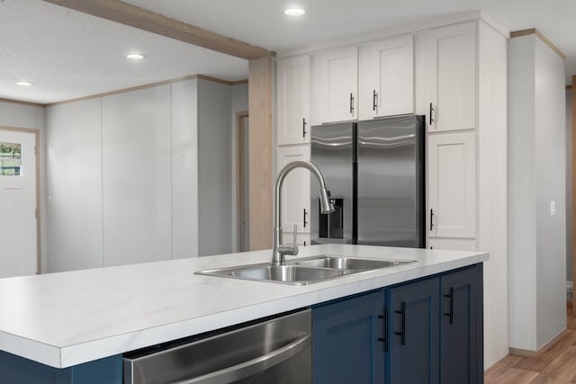 kitchen with white cabinets, blue cabinets, sink, light wood-type flooring, and appliances with stainless steel finishes