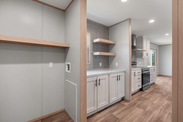 kitchen featuring wall chimney exhaust hood, stainless steel electric range, white cabinets, and light hardwood / wood-style flooring