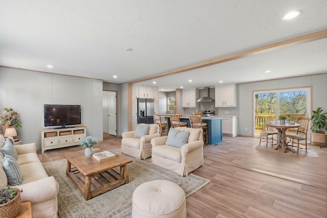 living room with beamed ceiling, a textured ceiling, and light hardwood / wood-style flooring