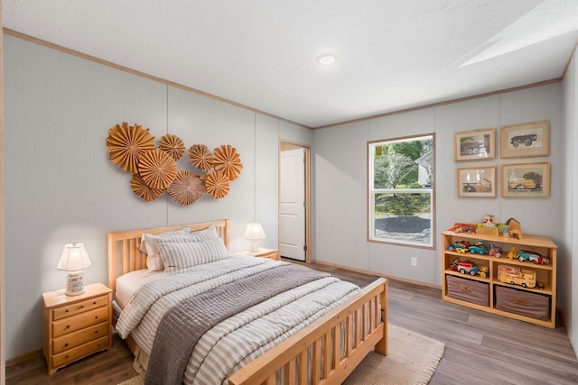 bedroom with crown molding, a textured ceiling, and hardwood / wood-style flooring