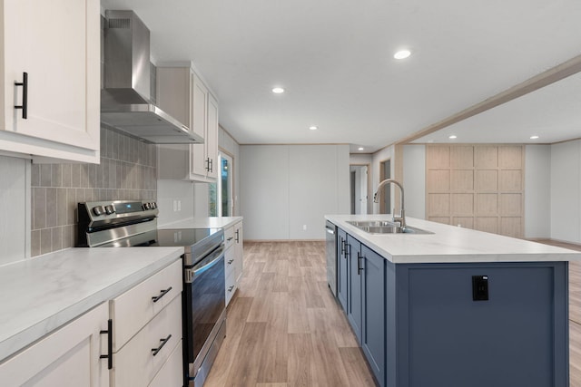 kitchen featuring sink, wall chimney exhaust hood, blue cabinetry, an island with sink, and stainless steel appliances