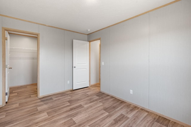 unfurnished bedroom with a closet, light hardwood / wood-style flooring, and ornamental molding