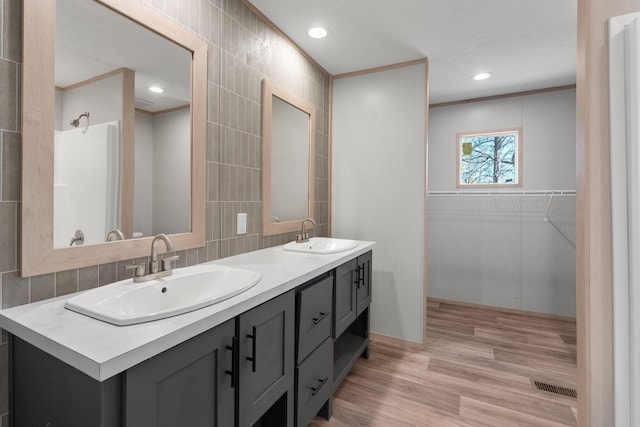 bathroom with hardwood / wood-style flooring, vanity, crown molding, and tile walls