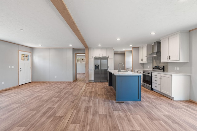 kitchen with wall chimney exhaust hood, stainless steel appliances, sink, light hardwood / wood-style floors, and an island with sink