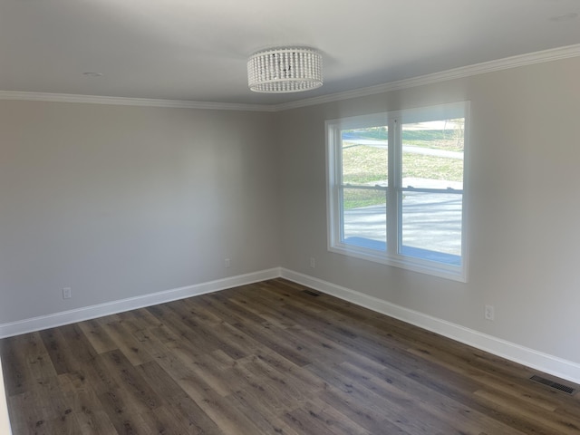 spare room with crown molding, dark wood-style floors, baseboards, and visible vents