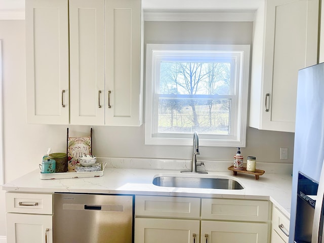 kitchen with light stone counters, a sink, stainless steel appliances, white cabinets, and crown molding