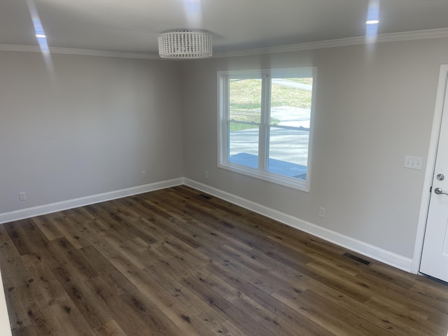 spare room with visible vents, baseboards, dark wood-style floors, and ornamental molding