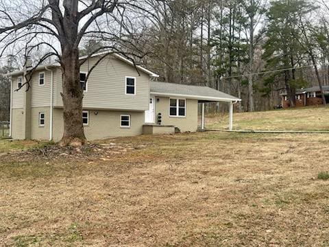 rear view of property featuring an attached carport and a lawn