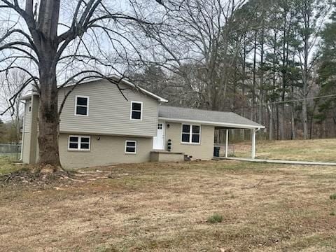 back of house with an attached carport and a yard