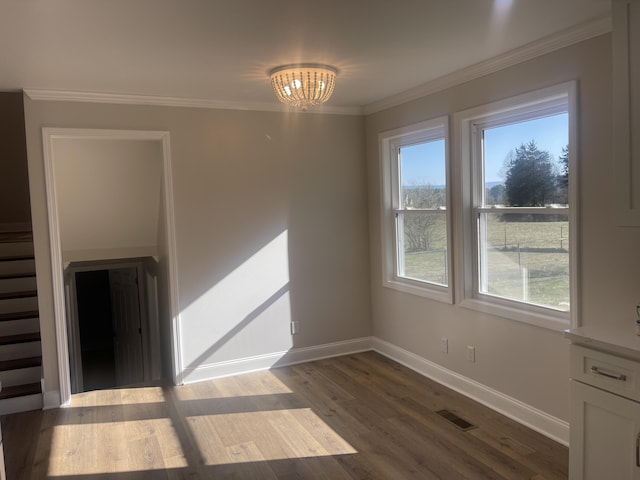 spare room featuring visible vents, baseboards, dark wood-style flooring, crown molding, and a notable chandelier