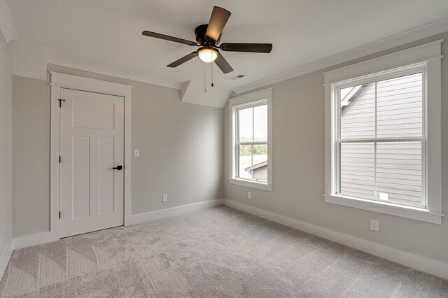 unfurnished room with ceiling fan, light colored carpet, and ornamental molding