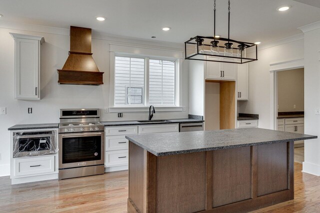 kitchen with custom exhaust hood, stainless steel appliances, sink, white cabinets, and a kitchen island