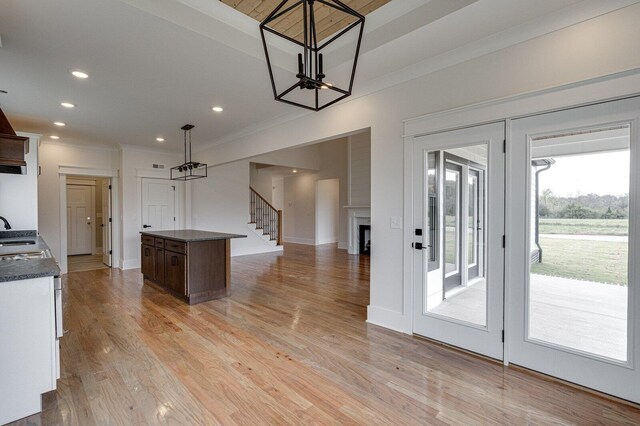 kitchen with crown molding, sink, light wood-type flooring, decorative light fixtures, and a chandelier