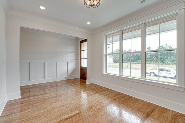 spare room featuring light wood-type flooring and ornamental molding