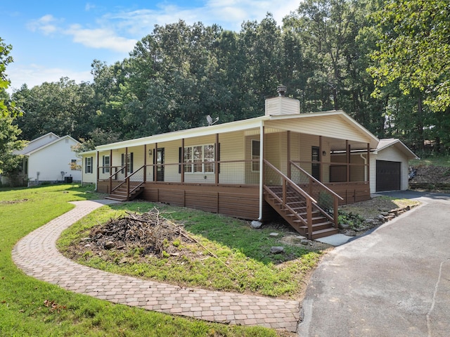 view of front of house featuring a porch, a garage, an outbuilding, and a front yard