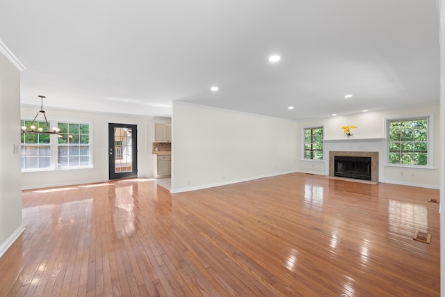 unfurnished living room with ornamental molding, light wood-type flooring, and a notable chandelier