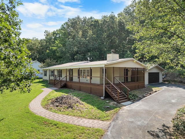 view of front of home featuring a porch, a garage, an outdoor structure, and a front yard