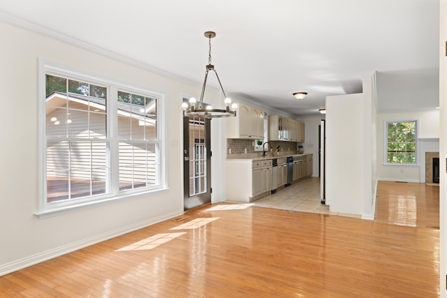 kitchen with backsplash, crown molding, decorative light fixtures, light hardwood / wood-style flooring, and a notable chandelier