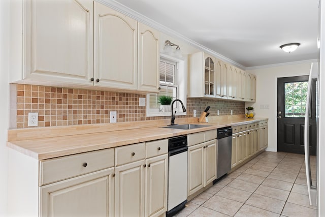 kitchen with backsplash, sink, light tile patterned floors, ornamental molding, and cream cabinetry