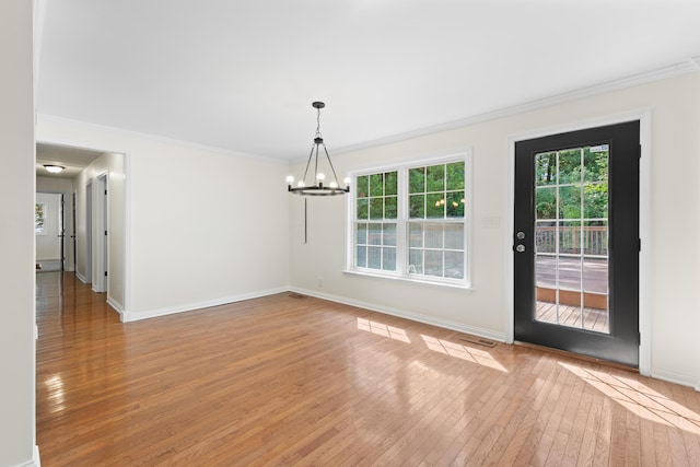 unfurnished dining area featuring hardwood / wood-style floors, crown molding, and a notable chandelier