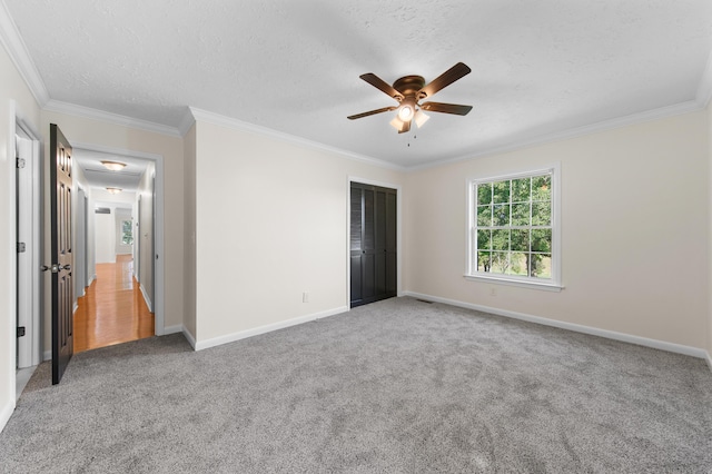 unfurnished bedroom featuring carpet, a textured ceiling, ceiling fan, and ornamental molding