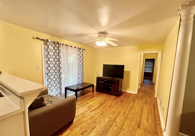 living room with decorative columns, ceiling fan, and light wood-type flooring