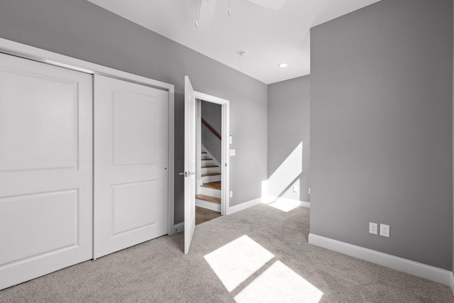 unfurnished bedroom featuring ceiling fan, light colored carpet, and a closet