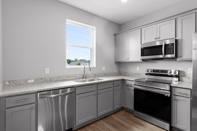 kitchen featuring gray cabinetry, sink, light stone countertops, and appliances with stainless steel finishes