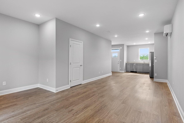 spare room with hardwood / wood-style flooring, sink, and a wall unit AC