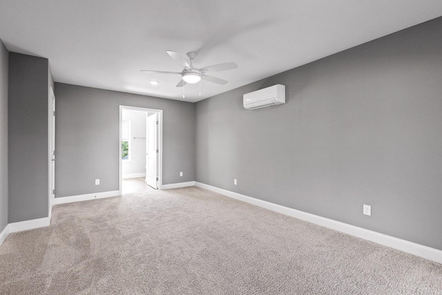 spare room featuring light colored carpet, a wall unit AC, and ceiling fan