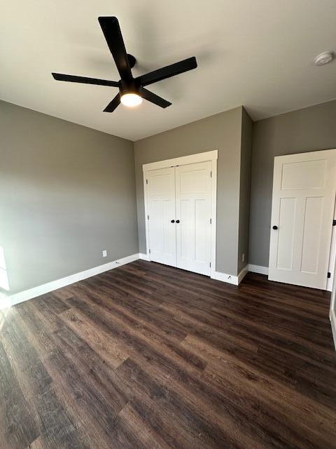 unfurnished bedroom with dark hardwood / wood-style flooring, a closet, and ceiling fan