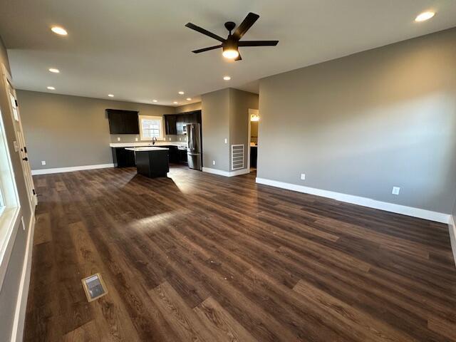 unfurnished living room with dark hardwood / wood-style floors, ceiling fan, and sink