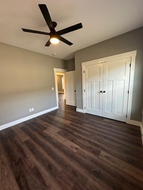 unfurnished bedroom with ceiling fan, dark hardwood / wood-style flooring, and a closet