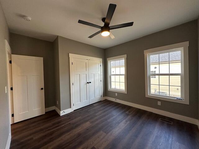 unfurnished bedroom with a closet, ceiling fan, and dark hardwood / wood-style floors