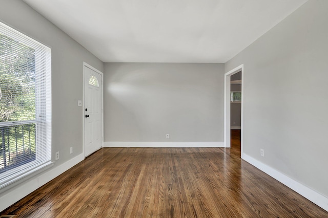 spare room with plenty of natural light and dark wood-type flooring