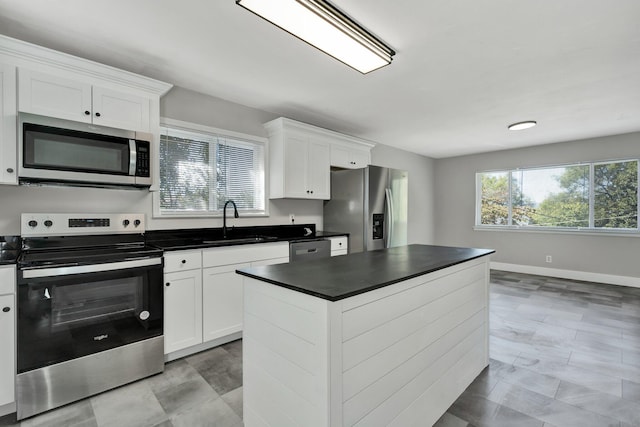 kitchen featuring a kitchen island, white cabinetry, sink, and appliances with stainless steel finishes