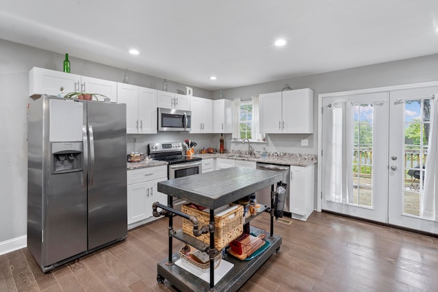 kitchen featuring appliances with stainless steel finishes, french doors, sink, wood-type flooring, and white cabinetry