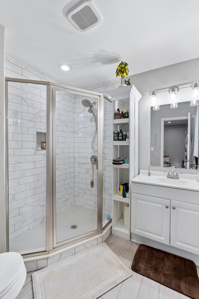 bathroom featuring tile patterned flooring, vanity, toilet, and an enclosed shower