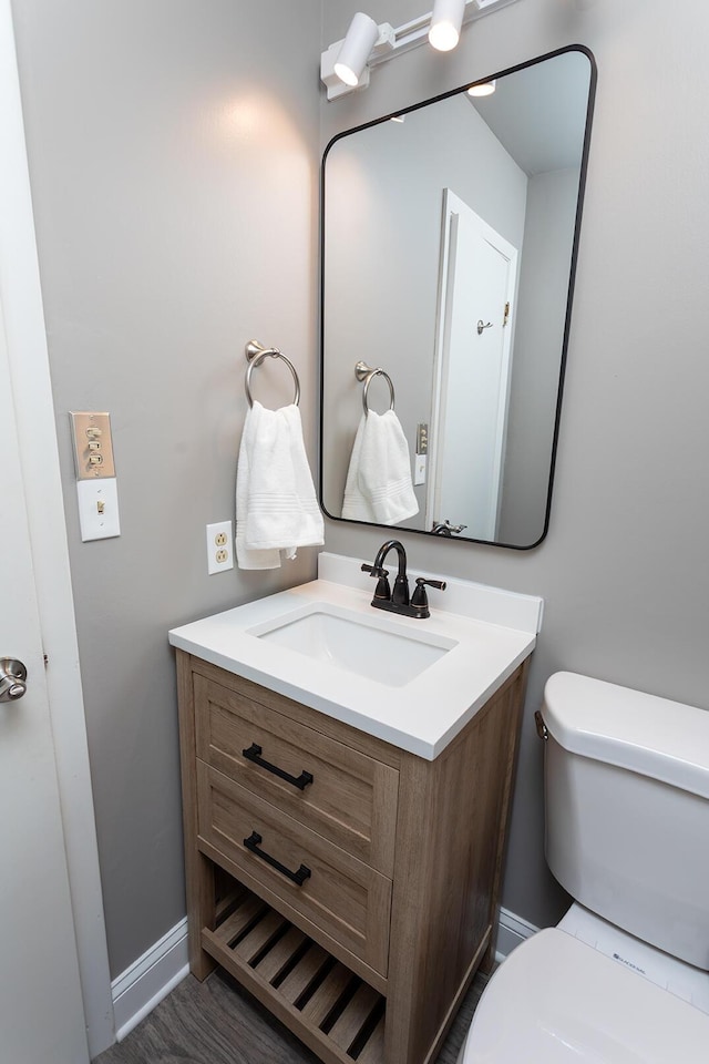 bathroom featuring baseboards, vanity, and toilet