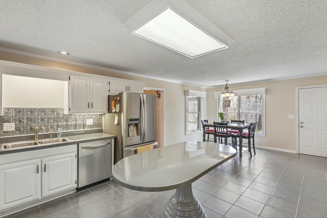 kitchen with crown molding, stainless steel appliances, white cabinetry, a sink, and backsplash