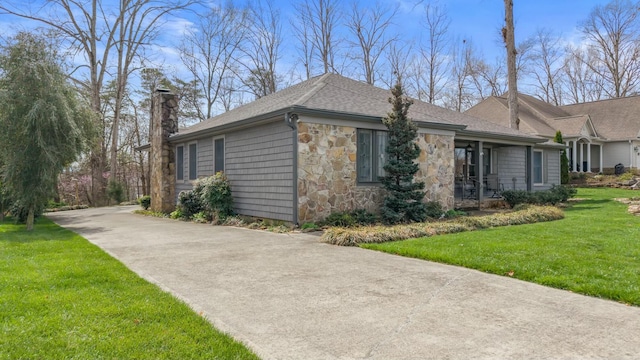 view of home's exterior with a lawn, stone siding, driveway, a shingled roof, and a chimney