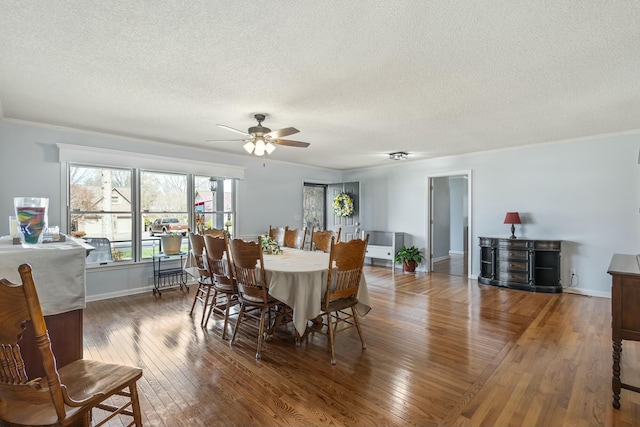 dining space with hardwood / wood-style floors, a textured ceiling, baseboards, and a ceiling fan