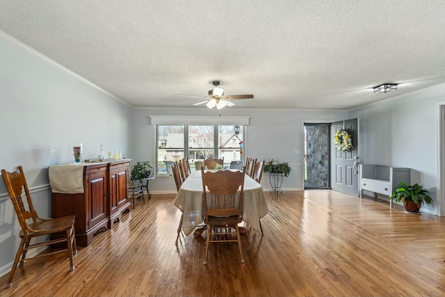 dining area featuring a ceiling fan, ornamental molding, and wood finished floors