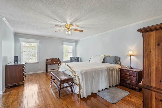 bedroom with a textured ceiling, crown molding, baseboards, and hardwood / wood-style floors