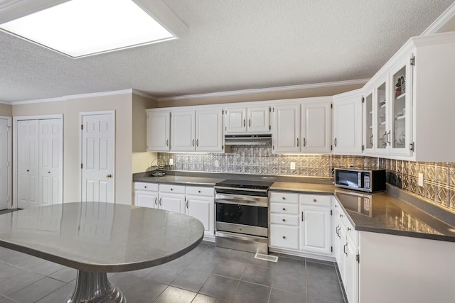 kitchen featuring white cabinetry, under cabinet range hood, backsplash, dark countertops, and appliances with stainless steel finishes