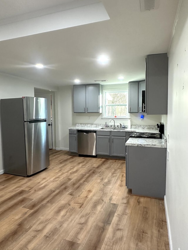 kitchen featuring gray cabinets, appliances with stainless steel finishes, sink, and light hardwood / wood-style floors