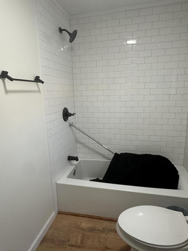 bathroom featuring tiled shower / bath, wood-type flooring, and toilet