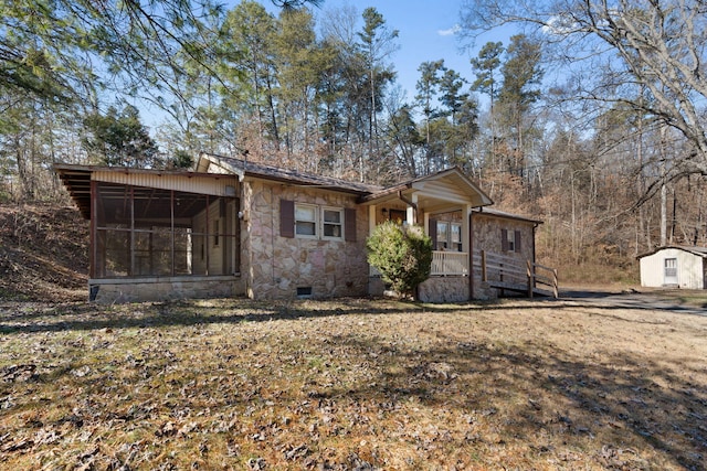 view of front of property featuring a shed, a front lawn, and a sunroom