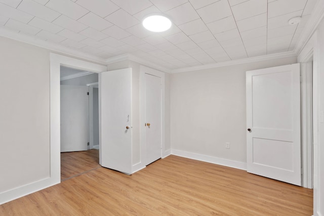 empty room with light hardwood / wood-style flooring and crown molding