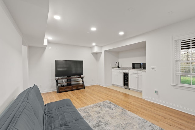 living room featuring beverage cooler, light hardwood / wood-style floors, and indoor wet bar